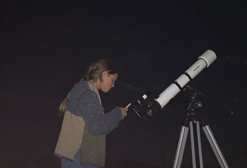 girl next to a telescope
